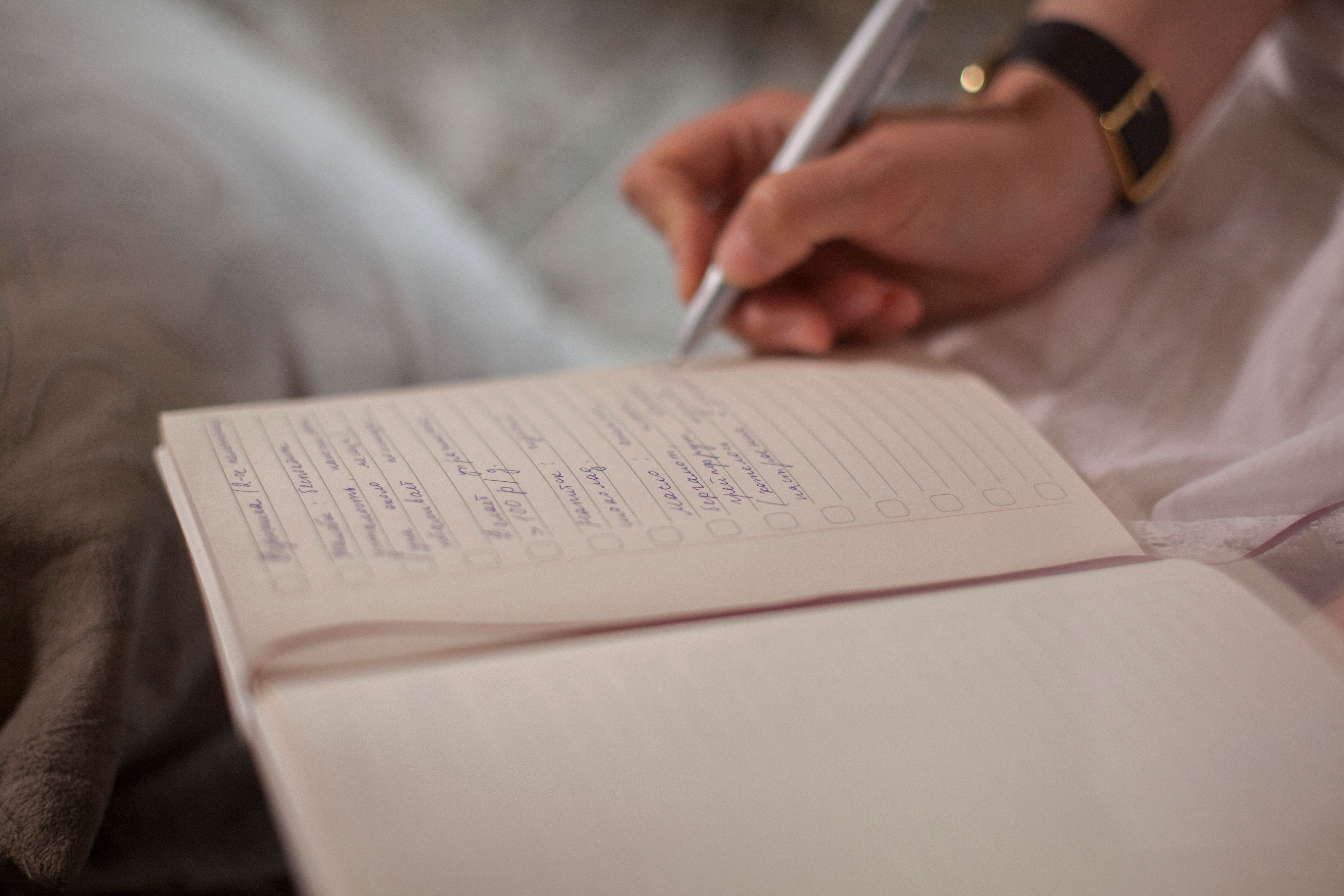 A close-up image of a person's hand writing in a notebook